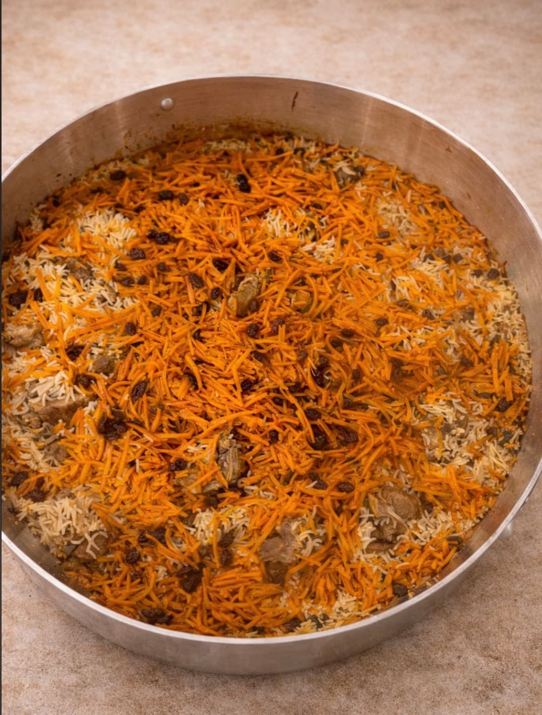 Afghani Pulao — rice with carrots in a large silver kazan