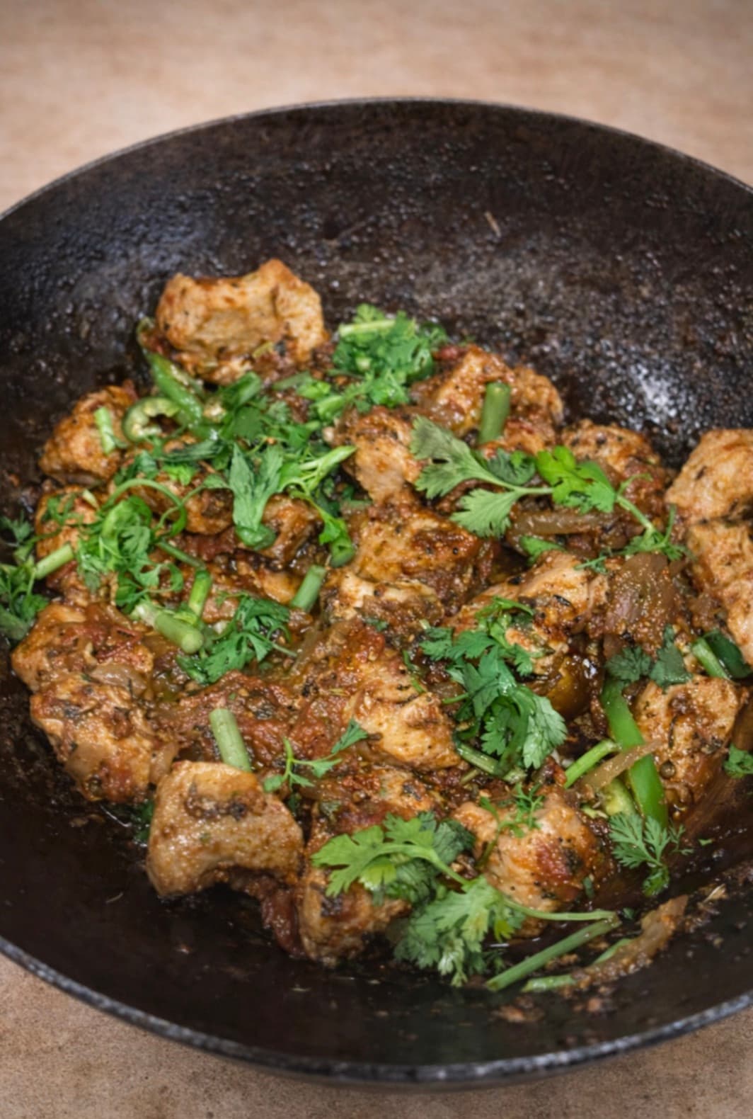 Qorma — slow-braised meat in a dark cast-iron wok